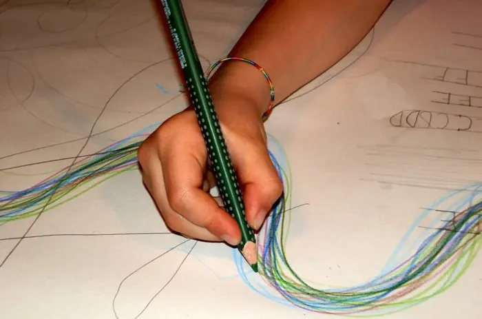 Mano di un bambino che traccia linee colorate su un foglio