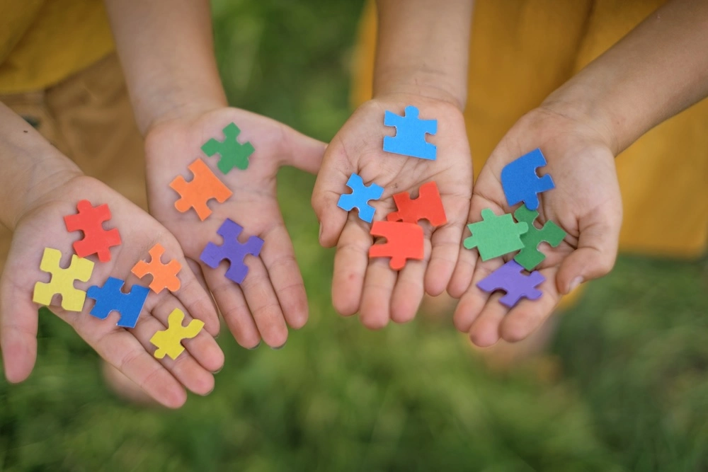 Mani di bambini che mostrano tessere di puzzle colorate