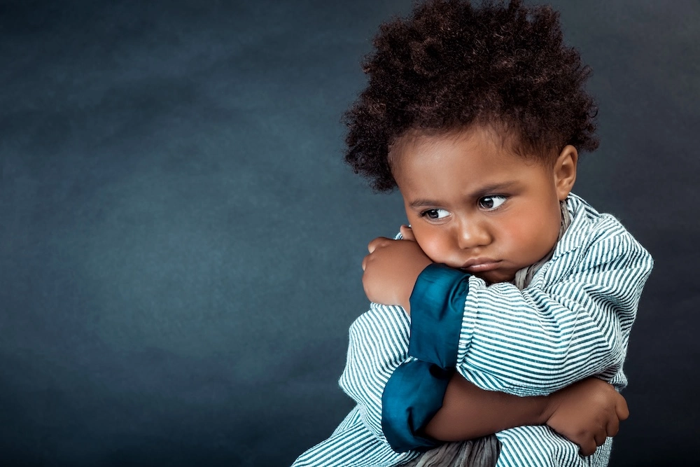 Bambino imbronciato con le braccia incrociate